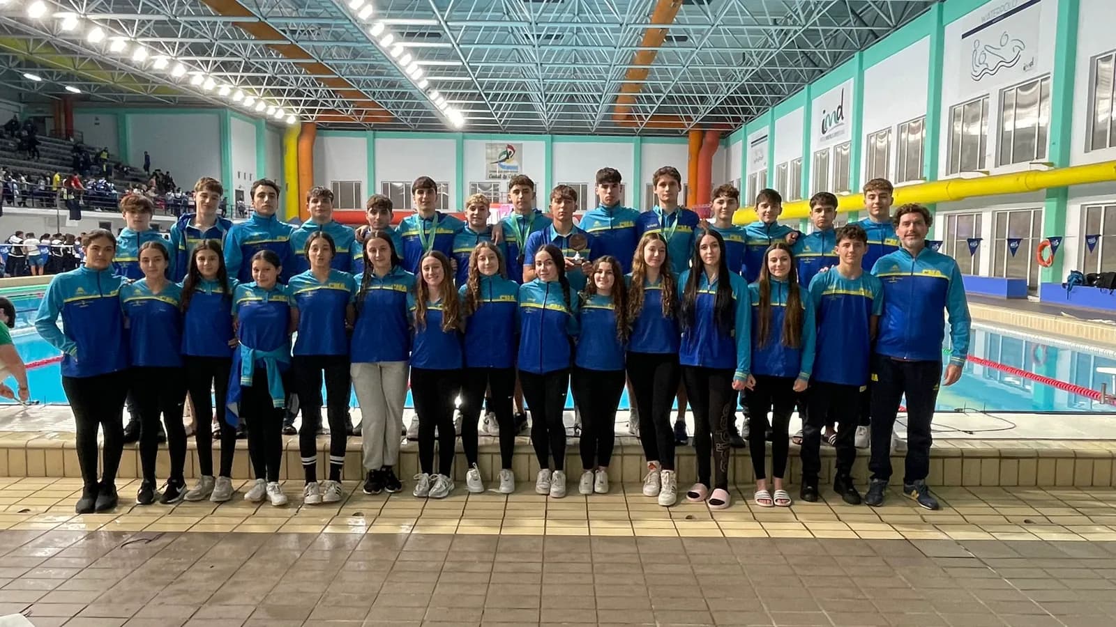 The club’s infantil and junior team in blue tracksuits, posing beside the indoor pool