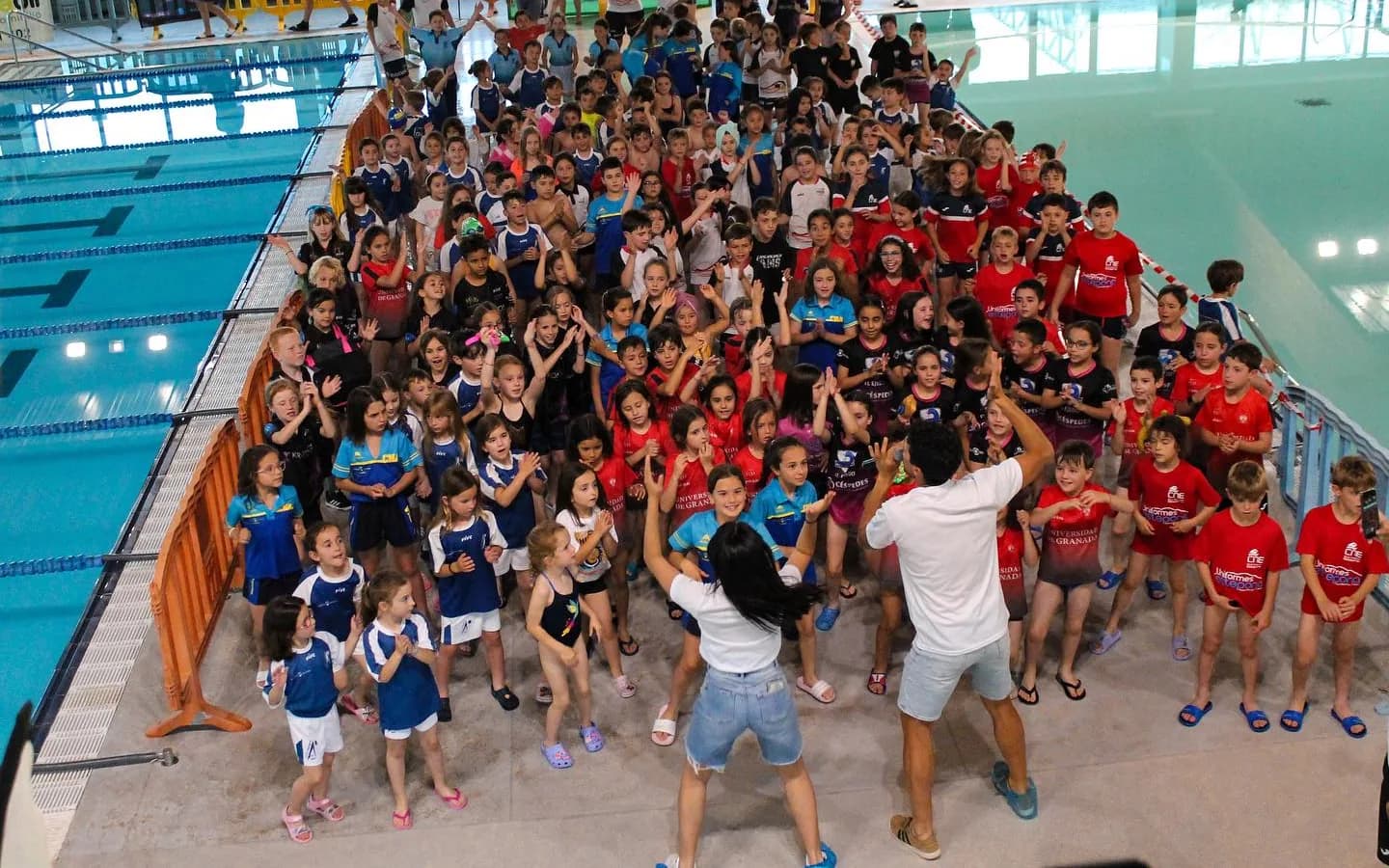 Overhead view of about two hundred children dancing on the pool deck at Torre del Mar with two entertainers, at the XII Open Chupete in May 2024