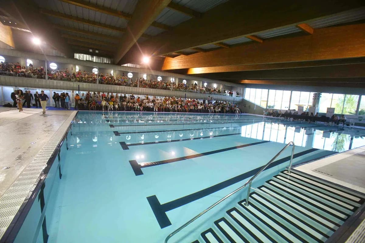 Indoor pool with no swimmers in the lanes and spectators in the stands